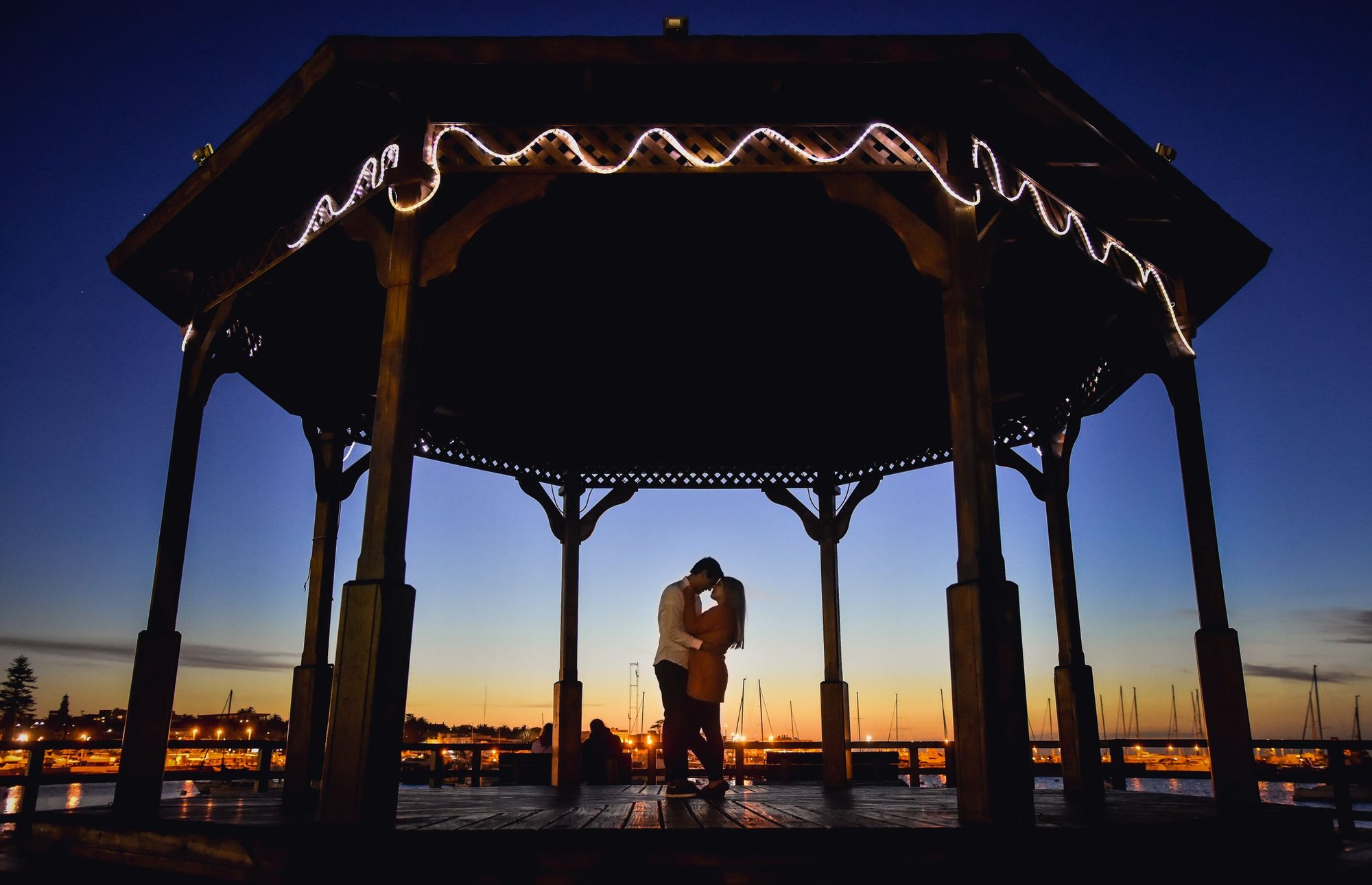 Pareja besándose bajo una glorieta iluminada